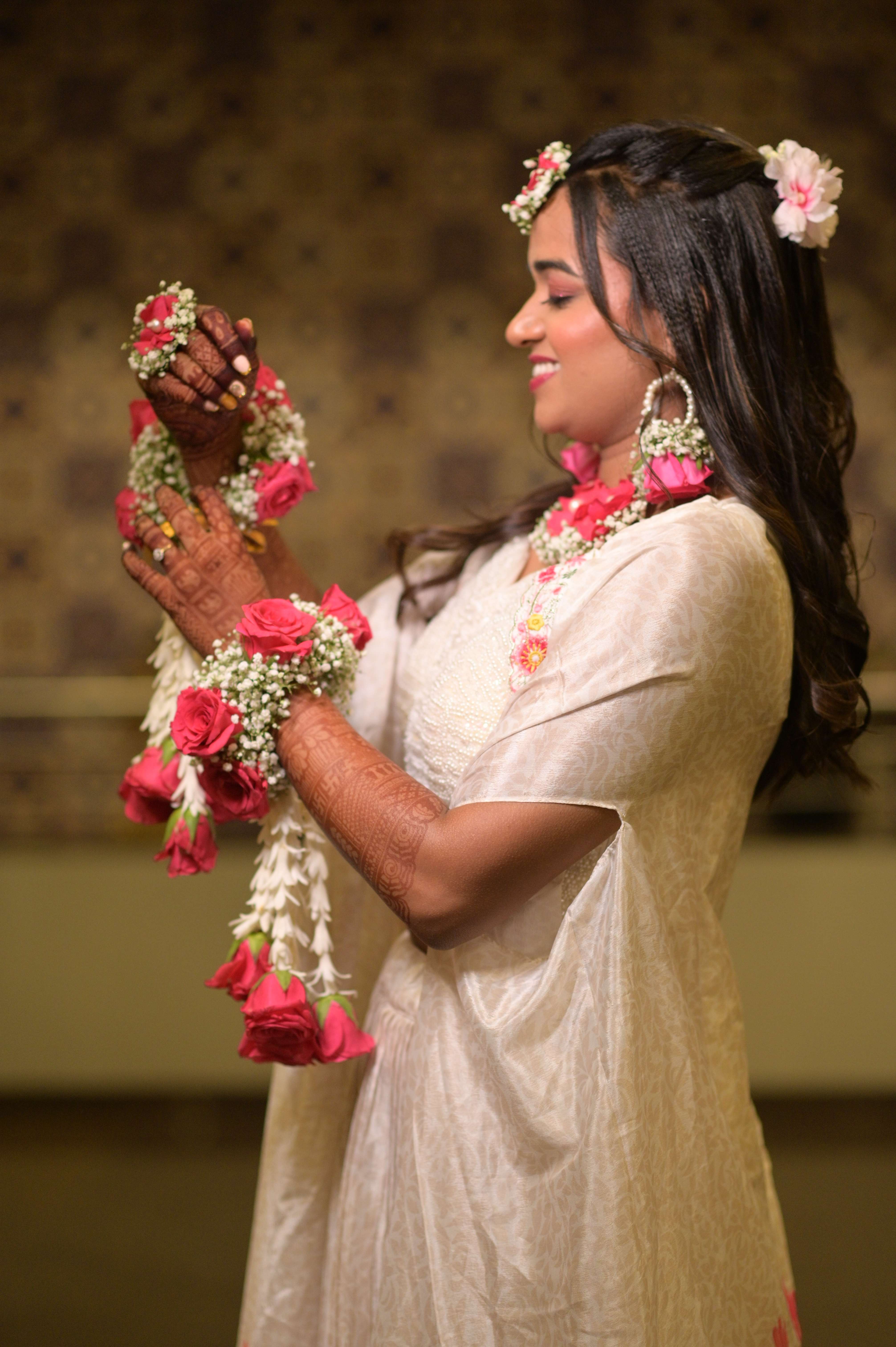 Candid bride with rose floral garland and henna hands